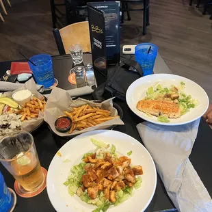 Mushroom Swiss burger, buffalo chicken Caesar salad, salmon Caesar salad and fries.