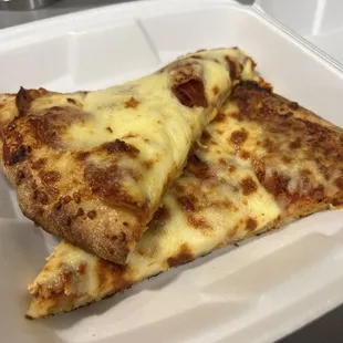 two slices of pizza in a styrofoam container