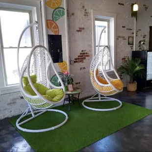 two hanging chairs in front of a brick wall