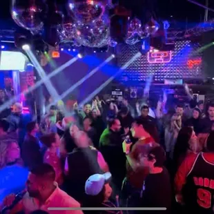 Dance floor over view. DJ is in the back. Bar and booths are in the left behind the TV.