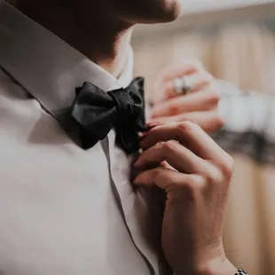A best friend ties the groom&apos;s bow tie for him