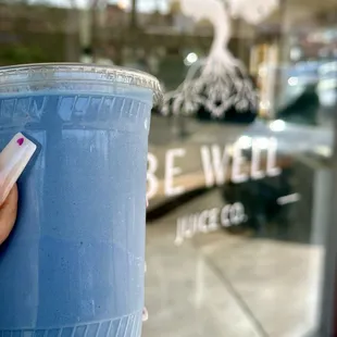 a hand holding a blue drink