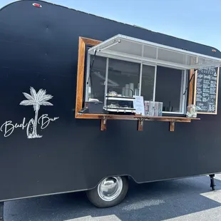 a black food truck parked in a parking lot