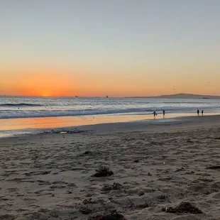 people walking on the beach at sunset