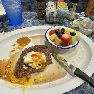 Ribeye with eggs and fresh fruit.