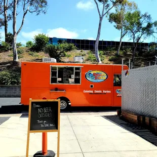 an orange food truck parked in a parking lot