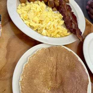 Sampler platter, including two eggs, two strips of bacon, home fries, and two pancakes.