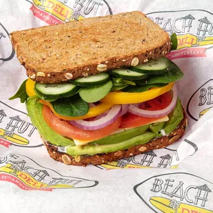 Vegan Vibes! It comes with sliced wheat, vegan Mayo, avocado, vegan Gouda, tomatoes, onions, bell peppers, cucumbers, and spinach.