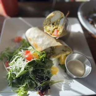 Breakfast burrito with tofu, hash cake bites, guacamole and tomato and side of arugula salad