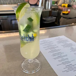 a drink in a glass with a lime wedge and a menu