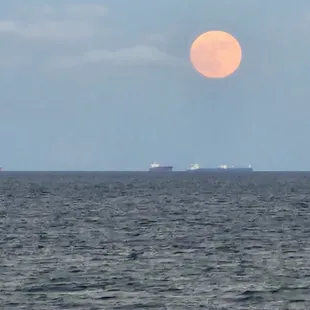 view from shared balcony of full moon rising over the Gulf of Mexico.