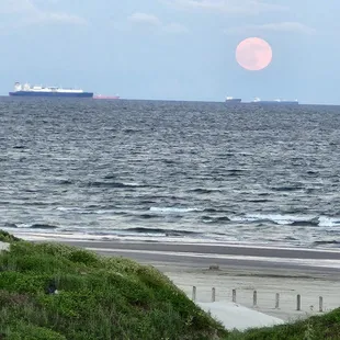 view from shared balcony of full moon rising over the Gulf of Mexico.