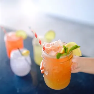 a person holding a mason jar with a drink in it