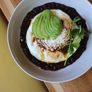 huevos rancheros - crispy corn tortilla, black beans, homemade salsa roja, queso fresco, cilantro, avocado, two eggs over medium