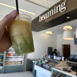 a hand holding a cup of green juice