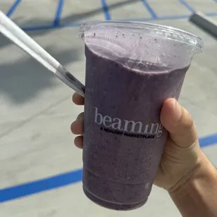  hand holding a purple smoothie