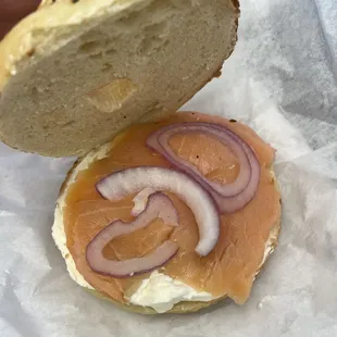 a person holding a bagel with a sandwich on it