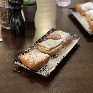 a wooden table with two plates of beignets