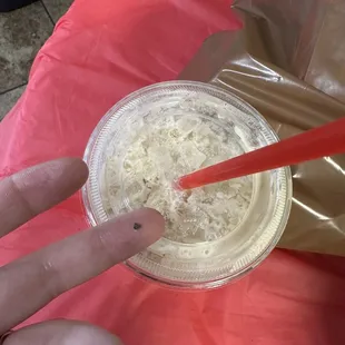 a hand holding a plastic cup of coffee