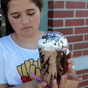 a young girl holding a chocolate milkshake