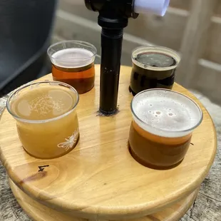 four different beers on a wooden tray