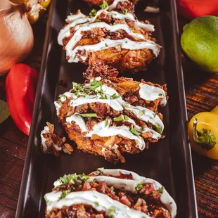 a row of baked potatoes with a drizzle of sour cream on top