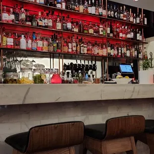 a bar with stools and shelves of liquor