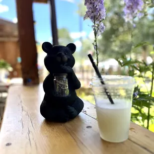 a glass of milk and a black bear figurine