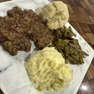 Chicken fried steak, mashed potatoes, green beans, cream gravy, and a homemade roll.