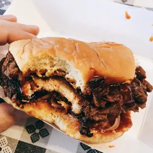 a hand holding a pulled pork sandwich