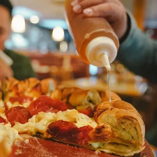 a man pouring ketchup on a pizza