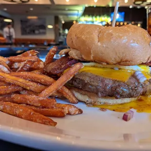 Brunch burger with a thick slab of bacon, sunny-side egg, and sweet potato fries.