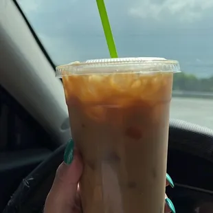 a hand holding a cup of iced coffee