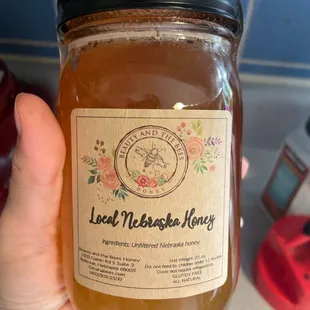 a hand holding a jar of honey