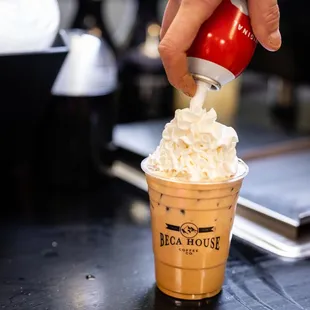 a hand sprinkleing whipped cream into a cup