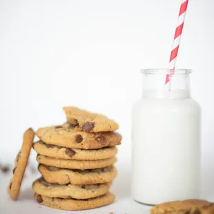 a stack of chocolate chip cookies next to a glass of milk