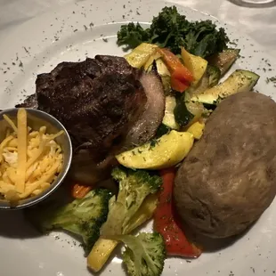 Bacon wrapped filet, baked potato, and veggies