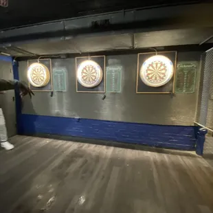 a man standing in front of a wall with darts on it