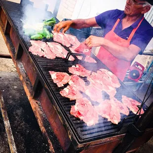 a man cooking steaks on a grill