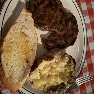 Rib Eye Steak, Baked Potato, and bread.