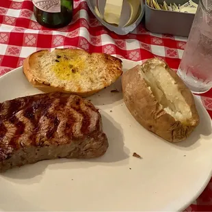 A 10 ounce ribeye steak, bread and baked potato.