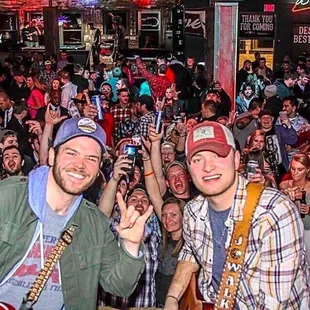 two men with guitars and a crowd of people