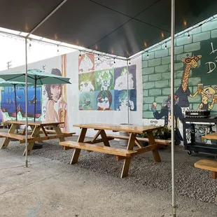 tables and umbrellas in front of a mural