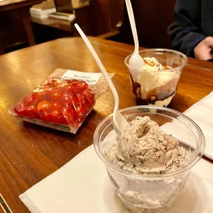 Chocolate chip cookie dough ice cream, vanilla sundae with hot fudge, and a bag of old fashioned cherries on a wire