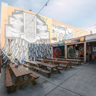 tables and benches in front of a mural