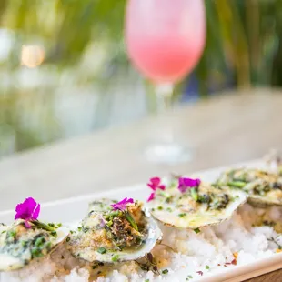 Oyster Côte d&apos;Azur - half dozen grilled oysters, wilted arugula, garlic, feta, pernod cream sauce, shallots, lemon, herb breadcrumbs.