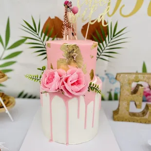 a pink and white cake with a giraffe topper