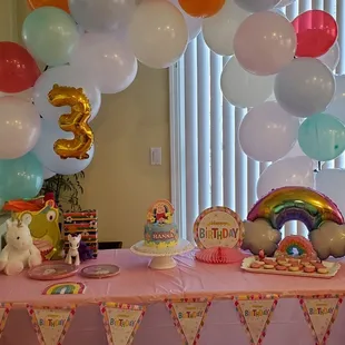 a table with balloons and a cake