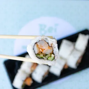 a close up of a sushi roll with chopsticks