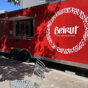 a red food truck parked in front of a building